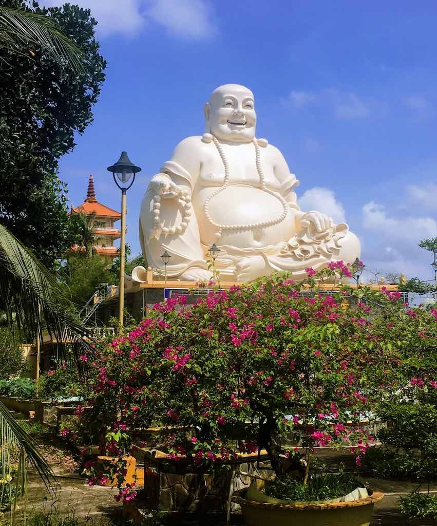 Fat Buddha: Who is the Laughing Buddha 6 Skinny Buddha vs Fat Buddha in Vietnam I Laughing Buddha statue at Vinh Trang Temple in Vietnam by WorldTravelConnector.com I buddha laughing I hotei buddha I laughing buddha I statue of laughing buddha I laughing buddha statue I happy buddha statue I budai I Chinese Jolly Buddha