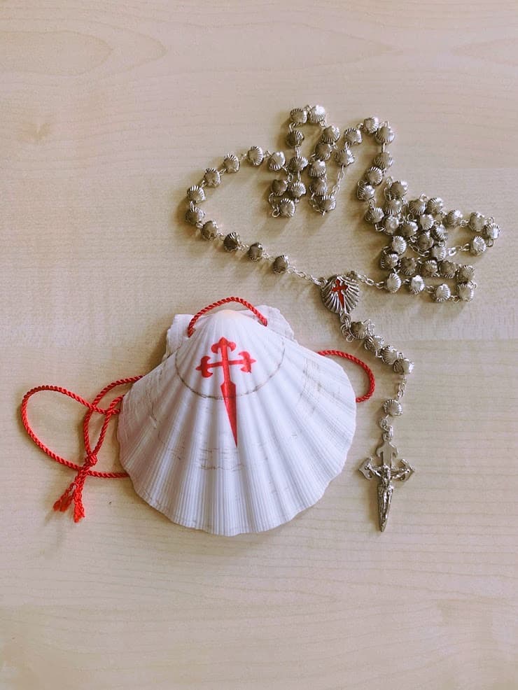 A scallop shell and a rosary  as souvenirs of  walking Camino del Norte in Spain 