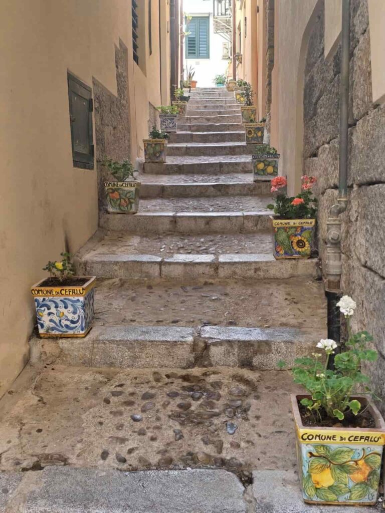 This Sicily’s Seaside Town Looks Straight Out of a Movie—Here’s What to Do in Cefalù 8 Vicolo Osnao with the glazed ceramic vases in Cefalu, Sicily